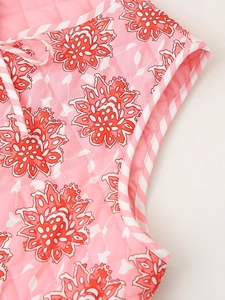 Close-up of pink floral quilted vest with red flower patterns and striped binding trim