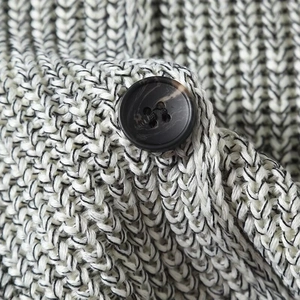 Macro shot of knit vest texture with a dark marble button and thick ribbed cotton pattern