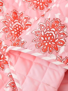 Close-up of pink floral quilted vest featuring red flower pattern and stitch texture