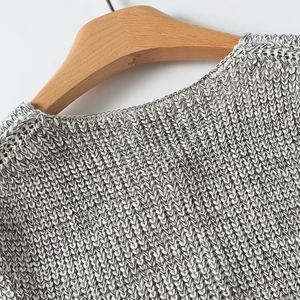 Close-up of the round neckline and textured grey mélange knit fabric on a wooden hanger