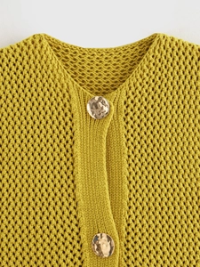 Dettaglio del cardigan giallo a maglia grossa con bottoni dorati e trama a maglia aperta