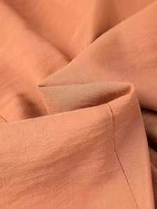 Close-up of orange V-neck backless dress featuring fine horizontal ribbed texture