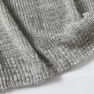Close-up of knit fabric showing black and white marl pattern and ribbed hem texture