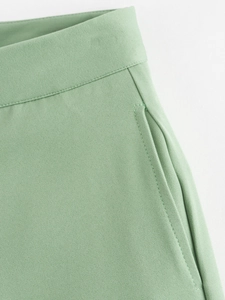 Détail macro du short en sergé vert clair montrant les coutures et la poche latérale
