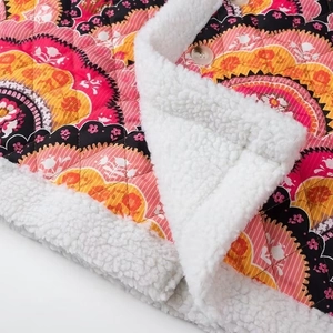 Détail d'une veste matelassée fleurie avec doublure sherpa blanche et bouton de fermeture