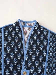 Detail of diamond quilted floral jacket with contrast piping and a wooden button closure