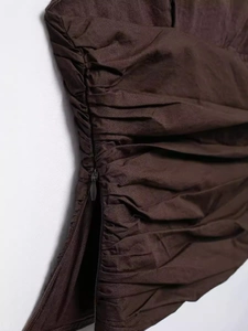 Detail of dark brown backless top featuring side invisible zipper and pleated fabric texture