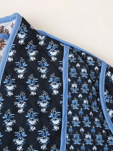 Detailed close-up of blue floral quilted fabric with diamond pattern and neat piping edge