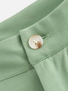 Vue détaillée du tissu sergé vert sauge et d'un bouton de haute qualité effet marbre