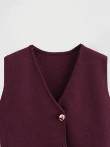 Détail du gilet en tricot bordeaux à col en V avec un bouton en métal doré poli brillant