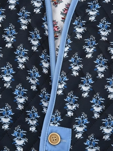 Detail of quilted floral reversible cotton jacket with dark blue pattern and button