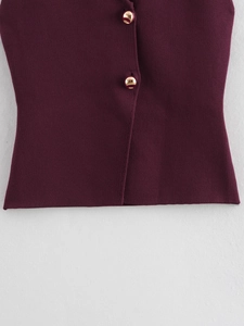 Détail des boutons dorés sur un gilet sans manches en tricot bordeaux avec col en V