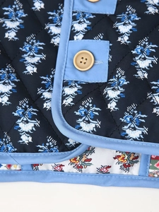Detail of reversible quilted vest featuring blue floral print and yellow round buttons