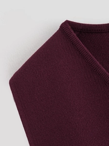 Détail macro du col en V côtelé et de la texture en maille fine sur le gilet bordeaux