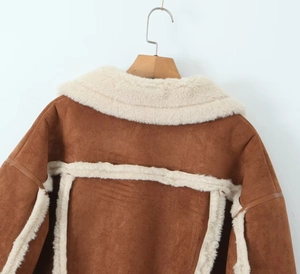Detail einer braunen Wildlederjacke mit weißem Lammfellkragen und weichen Nähten