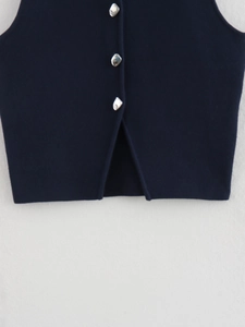 Detail of navy knit vest with irregular silver buttons and a split hemline design