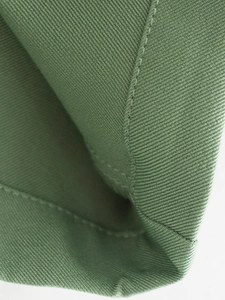 Gros plan sur le tissu en sergé vert avec double couture précise et texture de qualité