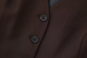 Close-up of high-quality dark brown twill fabric with black buttons on formal vest