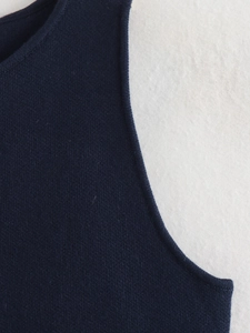 Detail of the navy blue knitted vest showing premium stitching on the neckline and armhole