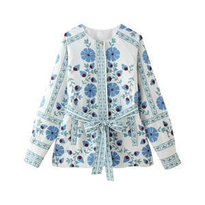 Detailed view of blue floral print patterns on white cotton padded jacket with tie waist