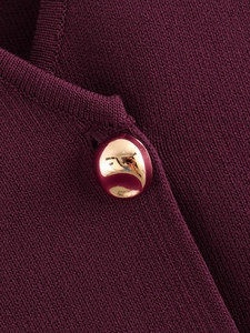Détail macro du tricot rouge bordeaux et d'un bouton métallique doré brillant