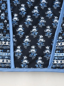 Close-up of diamond-quilted floral fabric with vintage patterns and blue contrast piping