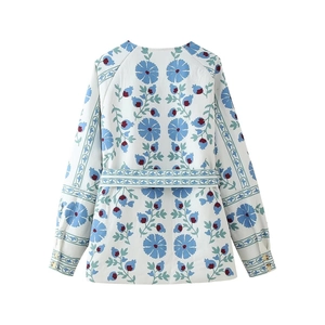 Detail view of the floral blue print and waist tie on the back of a white cotton jacket