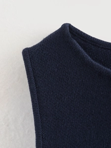 Detail of navy blue knitted vest neckline showing high-quality stitching and texture