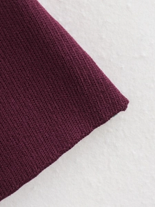 Vue macro du gilet en tricot violet foncé montrant la texture côtelée et la matière