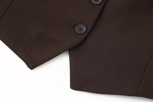 Detail view of woven brown vest fabric texture and black resin button closure