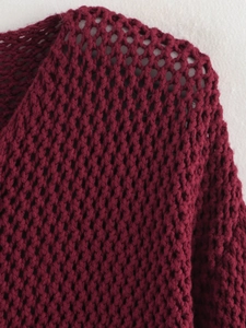 Close-up detail of burgundy coarse knit cardigan showing chunky open-work texture