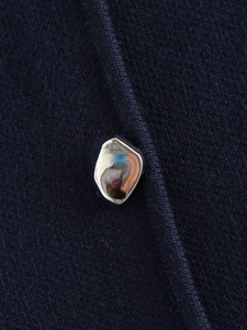 Macro shot of navy knit fabric with a unique irregular silver metallic button detail