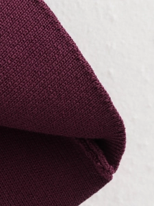 Vue macro détaillée de la texture en maille côtelée bordeaux profond du cardigan à col en V