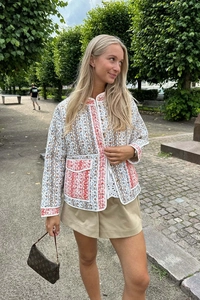 Detail of floral quilted jacket featuring printed patterns and contrast piping trim
