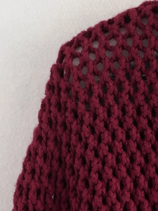 Detailed close-up of burgundy chunky knit texture featuring an open mesh hollow design