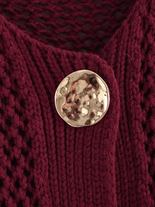 Macro detail of wine red chunky knit cardigan featuring textured gold metal button