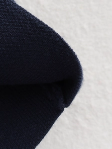 Close-up of navy blue rib-knit fabric texture with detailed wool blend fibers