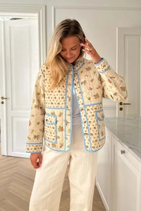 Detail of floral quilted jacket featuring light blue contrast piping and single-breasted buttons