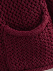 Detail shot of chunky knit burgundy cardigan with heavy weave texture and functional pocket