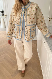 Detail of floral quilted jacket featuring blue piped edges and practical front flap pockets