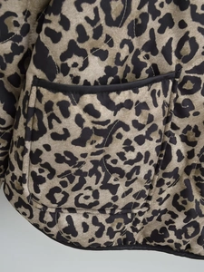 Close-up of leopard print quilted jacket showing diamond stitching and black piping pocket