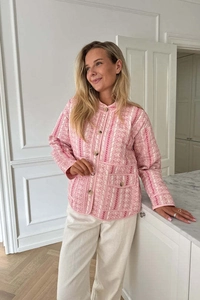 Detailed view of pink and white quilted jacket with contrast buttons and front flap pocket