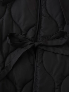 Close-up of black wave-quilted jacket featuring a delicate decorative ribbon bow tie detail