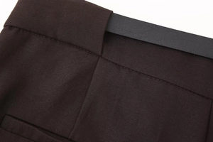 Detailed macro view of dark brown high waist pants with a textured black faux leather belt