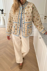Detail view of floral quilted jacket with blue piping and large front pockets