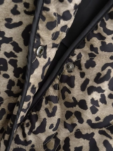 Macro detail of quilted leopard print jacket with silver snap buttons and black piping