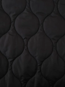 Close-up of black quilted fabric with wave stitching on the padded jacket