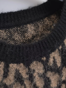 Dettaglio del girocollo a coste e della morbida trama leopardata del maglione in maglia