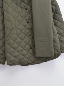Détail de veste matelassée vert armée avec losanges et écharpe rembourrée assortie