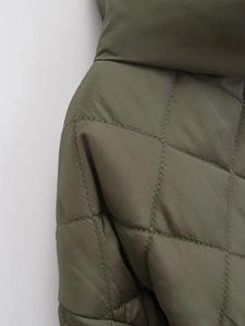 Détail d'une veste matelassée vert olive montrant les coutures et motifs en losanges